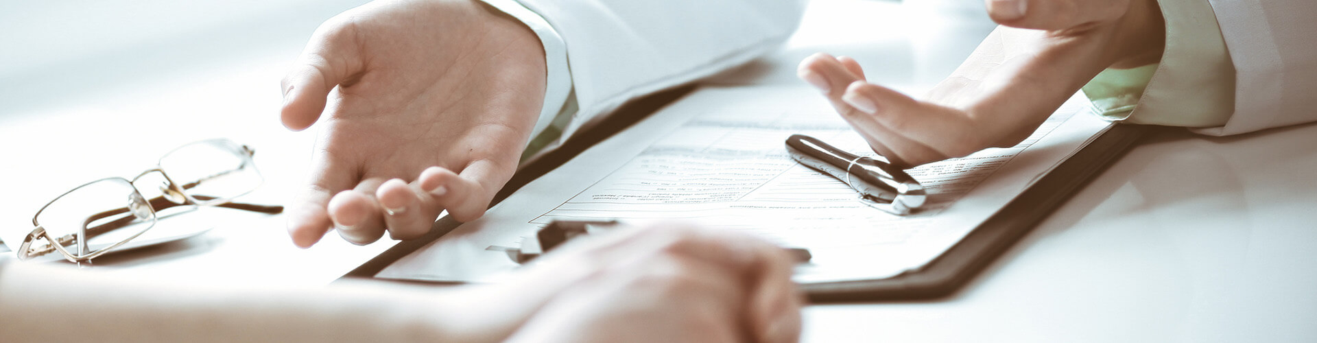 A doctor sits at a table in their office explain the results on a clipboard