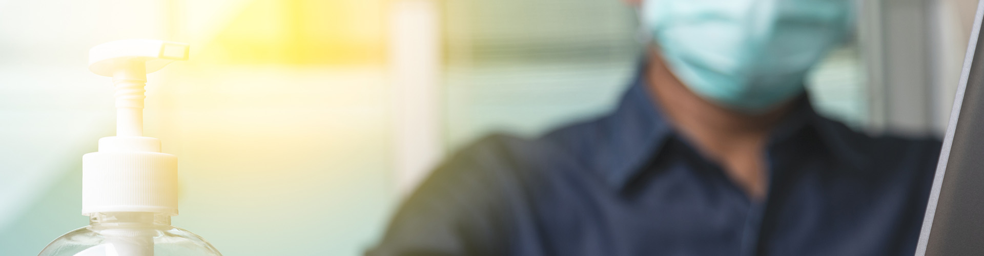A person wearing a mask looking at a bottle of hand sanitizer
